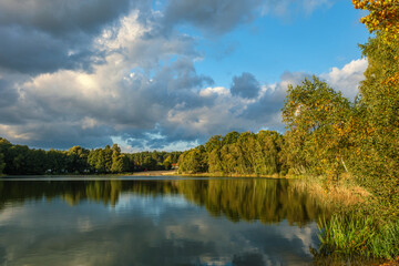 Fototapeta premium Natural landscape of the lake, high definition, the movement of waves against the background of the autumn forest. The reflection of clouds on the ripples of water. Germany.