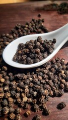 Pepper in white spoon in wooden background. 