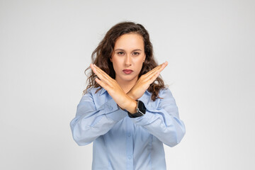 A determined young woman in a blue shirt makes an X sign with her arms