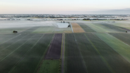Aerial drone view of meadow landscape in The Netherlands on a sunny, foggy morning. Misty low clouds farmland landscape captured from above.