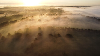 Aerial drone view of meadow landscape in The Netherlands on a sunny, foggy morning. Misty low...