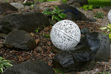 Wicker white lamps imitation balls of thread lie on a flower bed