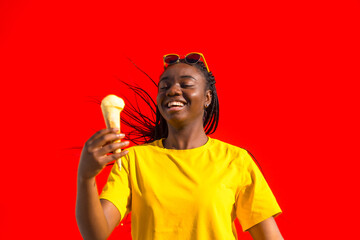 Cheerful african woman with an ice cream against red wall