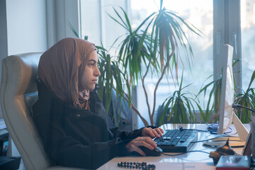 Muslim female working in office using computer with white background, represent power of arabian woman