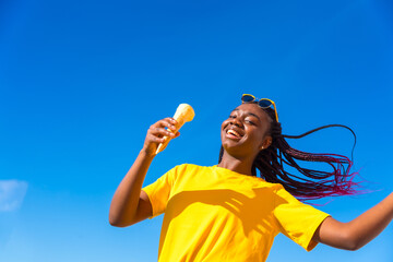 Happy african woman dancing while eating ice cream outdoors