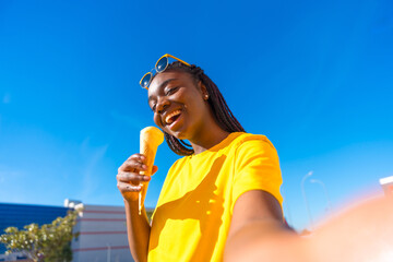 African woman taking a selfie while eating ice cream outdoors