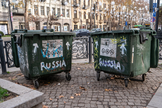 Trash cans marked with anti-Russian graffiti on Tbilisi streets, protesting against the politics of Russia, capturing a moment of social expression.