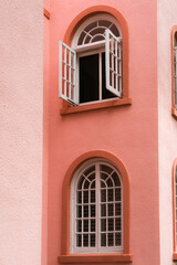 Fototapeta na wymiar Peach colored vintage building detail exterior with arched windows and doors in the color of peach fuzz.