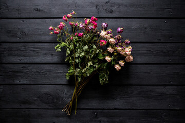 A bouquet of dried roses on a black wooden board, a bouquet of dried flowers