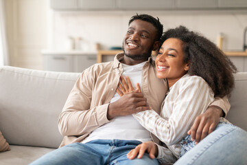 Cheerful African American Lovers Couple Cuddling Relaxing In Living Room