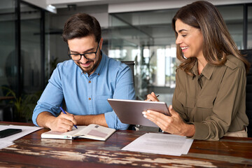 Professional happy middle aged business woman manager explaining work strategy teaching young...