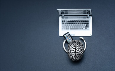 Steel Brain Holding Mobile Phone at Laptop