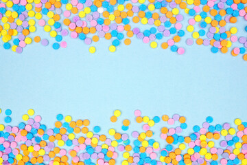 Fototapeta na wymiar Colorful candy sprinkles double border. Above view on a blue banner background. Pastel Easter color theme. Copy space.