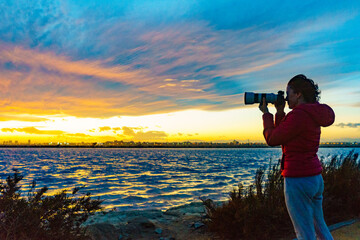 Woman taking photo from sunset over sea