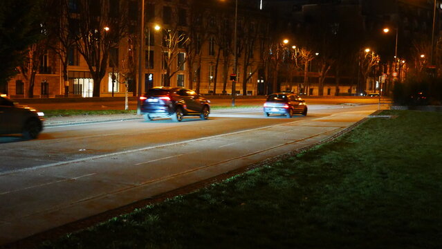 Circulation dans une grande avenue parisienne, la nuit tombée, éclairé par des lampadaires et des phares, fluide, promenade nocturne, sortie entre amis, quelques cyclistes, beauté urbaine, effet photo