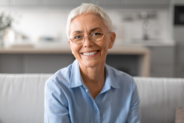 Fototapeta na wymiar Closeup portrait of happy senior lady with stylish eyeglasses indoor