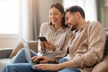 Young couple with phone and laptop enjoying time together
