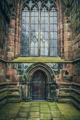 Not main entrance to oldest cathedrals in Nantwich with mossy stone and large stained glass windows, Cheshire, UK