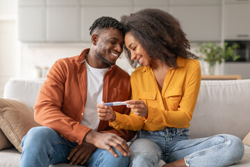 Loving African Man And Woman Holding Positive Pregnancy Test Indoor