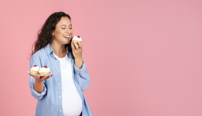 Hungry Expectant Lady Eating Sweets Standing Over Pink Studio Background