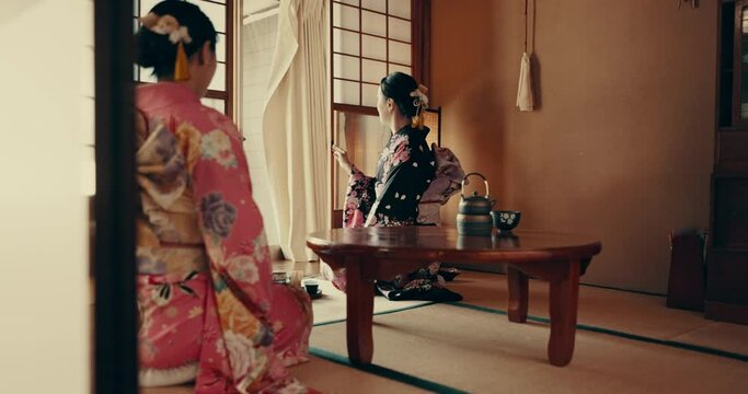 Women in traditional Japanese house with tea, kimono and relax together with mindfulness. Friends visit at calm tearoom with matcha drink, zen culture and connection sitting at table for wellness.