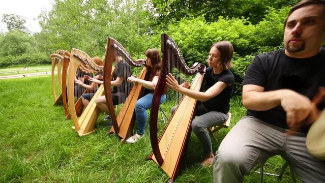 Man play on drum and six women and men play on arpas in row