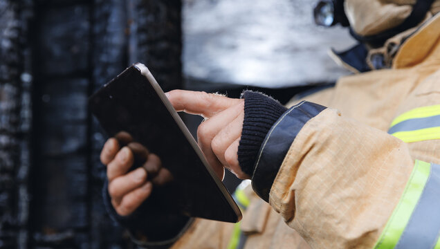 Control safety after burning apartment. Fireman inspector officer inspects burnt house, take photo on tablet for report of investigating incident fire