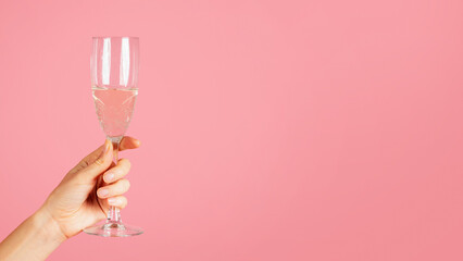 A close-up image showing a hand elegantly holding a sparkling champagne flute with effervescent...