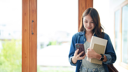 Female Asian university  wearing headphone using  smartphone listening music..