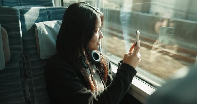 Train, phone and woman in city for travel, commute and journey on metro transportation in town. Passenger, vehicle and Japanese person take picture on smartphone with motion blur on public transport