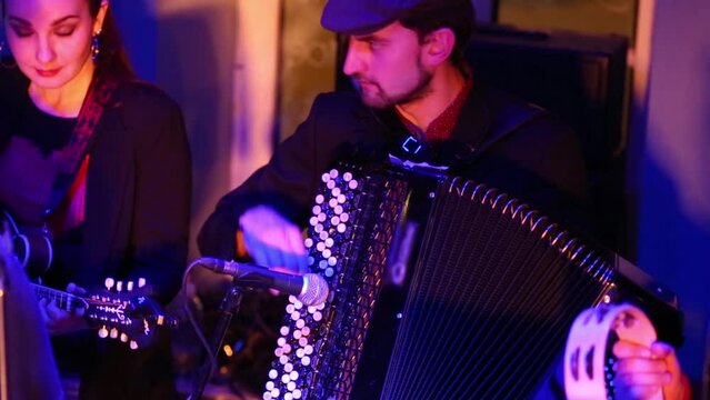 Two musicians of band are playing on guitar and accordion 