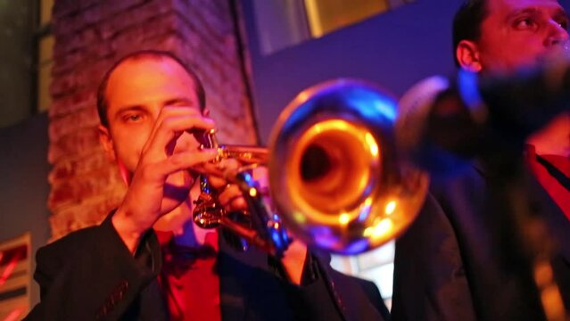 Men with trumpet and sax of band are playing music at musical bar.