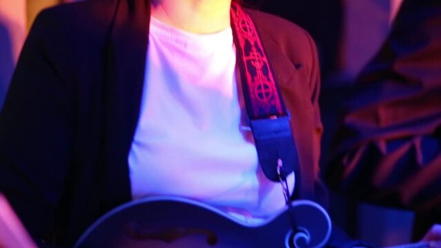 One woman of band is playing on the guitar at musical bar, close up view.