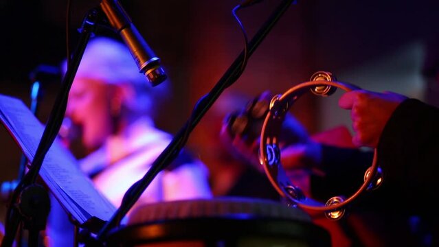 Musician of band is holding and playing on the tembrel at musical bar