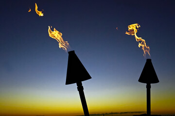 Hawaiian, Polynesian Pacific island modern natural gas tiki torch flames at sunset at tropical...