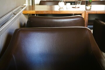 Innenausstattung von Café mit braunen Stuhllehnen aus Leder und Tisch 