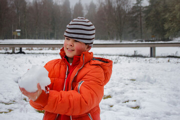 Adolescente com uma bola de neve na mão e vestido a rigor para o frio.