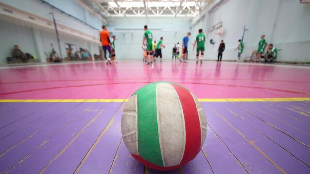 Ball is standing on the floor behind a volleyball players, close up view.