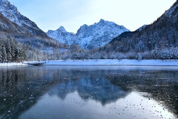 View of Razor and Križ mountains in Julian alps and a reflection in the ice covered surface of lake Jasna near Kranjska Gora, Slovenia