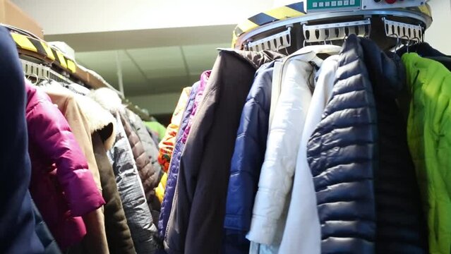 Row of fat winter coats turning in machine in big check-room.
