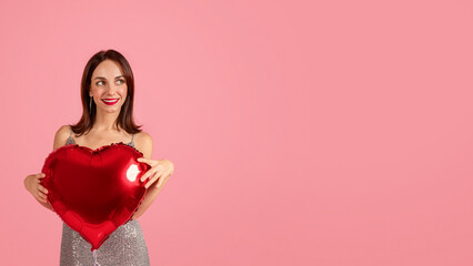A woman with a captivating smile holds a red heart-shaped balloon