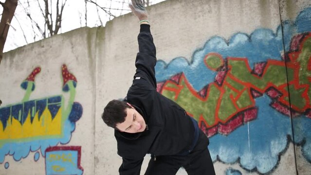 Man stand in Utthita Trikonasana yoga position near wall with graffiti