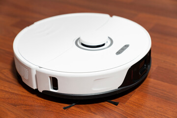 robot vacuum cleaner in modern smart home, robotic vacuum cleaner on wooden or laminate or parquet floor, cleaning dust on tile floors. Modern smart cleaning technology housekeeping.