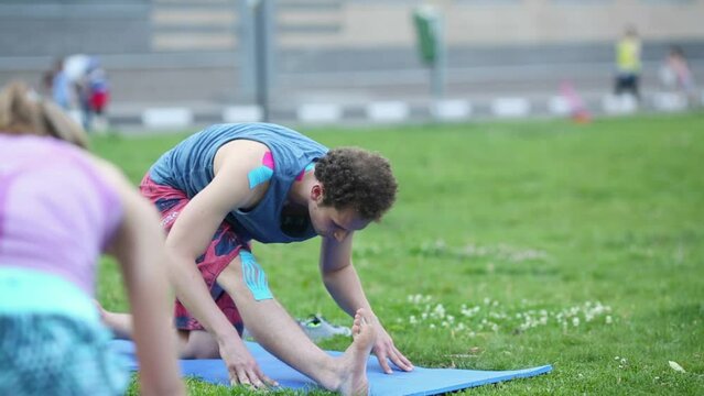 Yoga teacher bend to pulled leg in Losinyi Ostrov complex yard