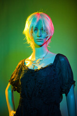 Mannequin wearing short white hair posing in a colorful studio lighting