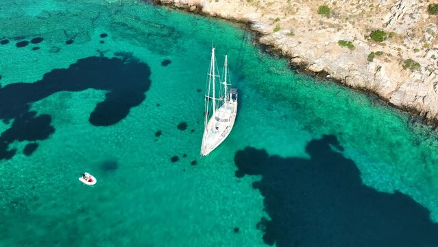 Aerial drone cinematic video of sail boat anchored in exotic paradise volcanic island complex forming a blue lagoon in tropical destination