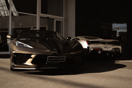 Metallic Brown Chevrolet Corvette C8 and silver Ferrari 488 Pista parked side by side - High Resolution Image
