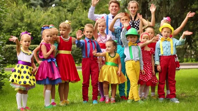 Fifteen children of different ages in bright clothes standing 