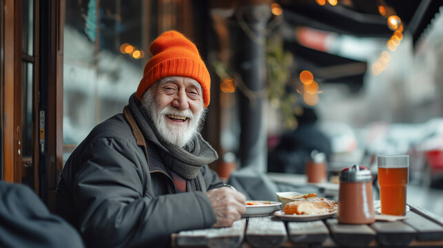 Homeless elderly man is sitting at an outdoor table, eating a plate of food at a place dedicated to helping the poor.
