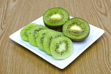 Sliced ​​kiwis arranged on a plate on a wooden table.
